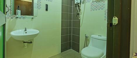 Un baño con lavamanos, inodoro, ducha y espejo.