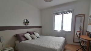 Een slaapkamer met een bed, nachtkastje en een raam met gordijnen.