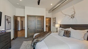 Una camera da letto con un letto grande, un armadio in legno, uno specchio e una scultura a parete.