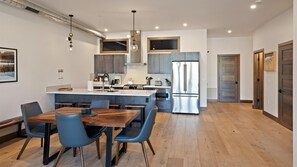 Una cucina moderna con isola centrale, elettrodomestici in acciaio inossidabile e zona pranzo con sedie blu.