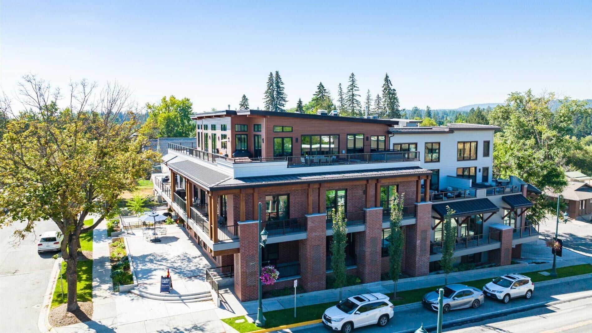 A modern building with a flat roof, large windows, and a covered outdoor seating area.
