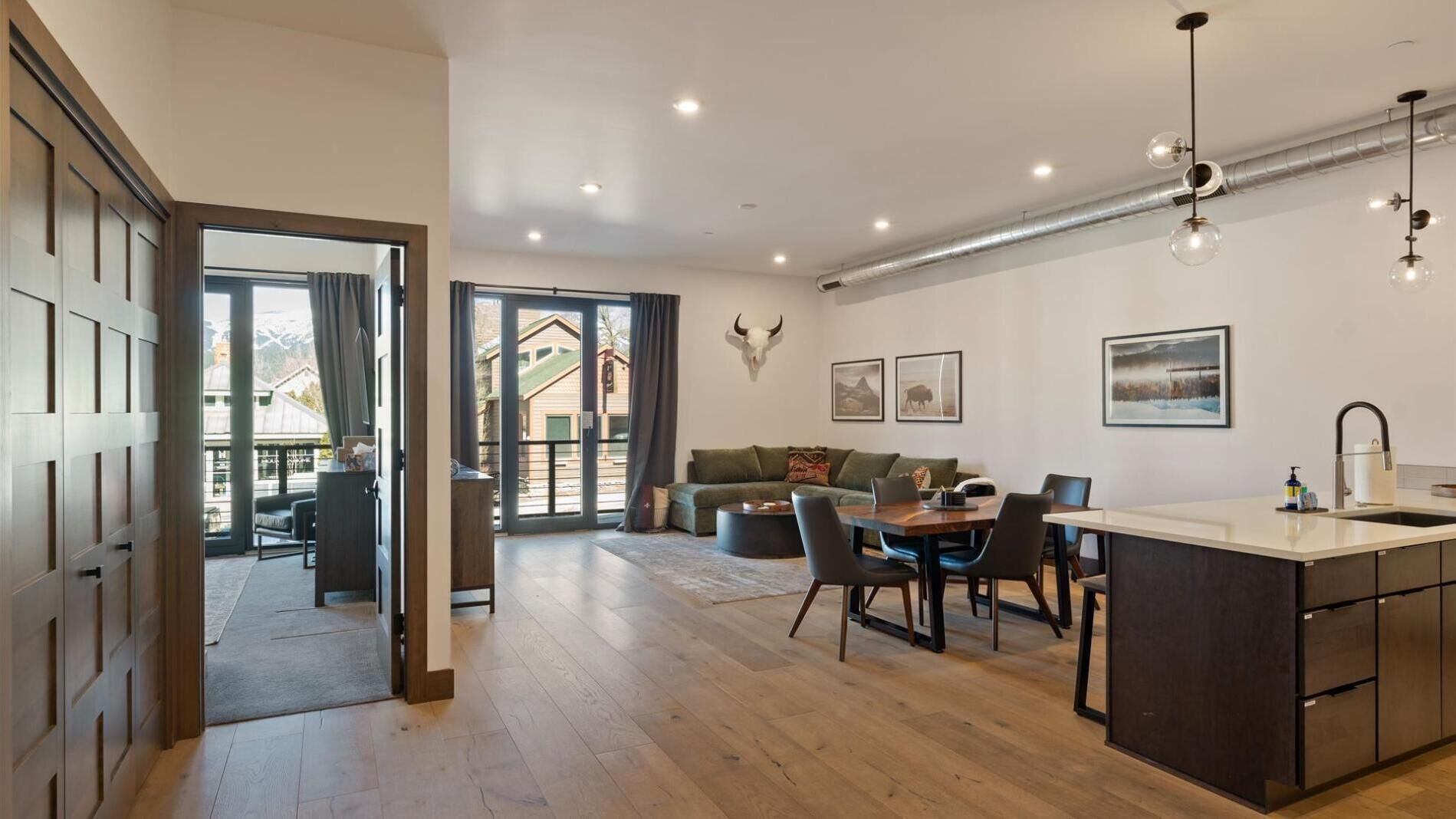 A spacious living area with a dining table, sofa, and a kitchen island with a sink.