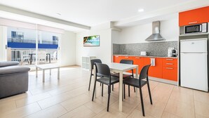 Une cuisine moderne avec un coin repas, de grandes fenêtres et une vue sur un balcon.