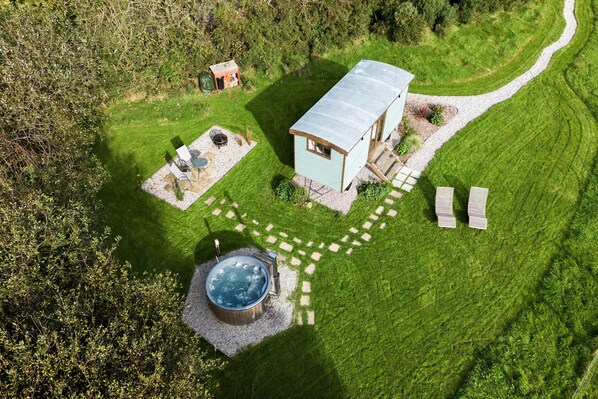 A small, single-story house with a metal roof, surrounded by a well-maintained lawn and a gravel path. - Fern (Bude)
