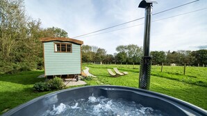 Ein Whirlpool mit Blick auf eine kleine Holzhütte und einen Metallpfosten in einer Wiese.