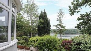 A stone-paved patio with potted plants and a view of a lake. - Ynys Castell (Menai Bridge)