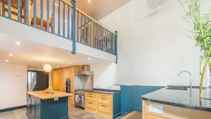 A modern kitchen with a central island, wooden cabinets, and a two-tiered wooden staircase. - 12 bedroom accommodation in Pembroke (Pembroke)