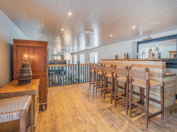 Zona de bar de madera con diseño rústico, que incluye una barra de madera y taburetes.
