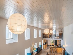 Un interior espacioso con techos altos, ventanas amplias y una zona de cocina.