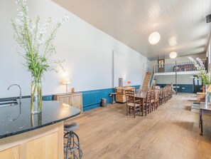 A spacious kitchen with a central island, wooden bar stools, and a dining area with multiple chairs.