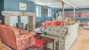 A cozy living room with a fireplace, patterned sofas, and a wooden floor. - 12 bedroom accommodation in Pembroke (Pembroke)