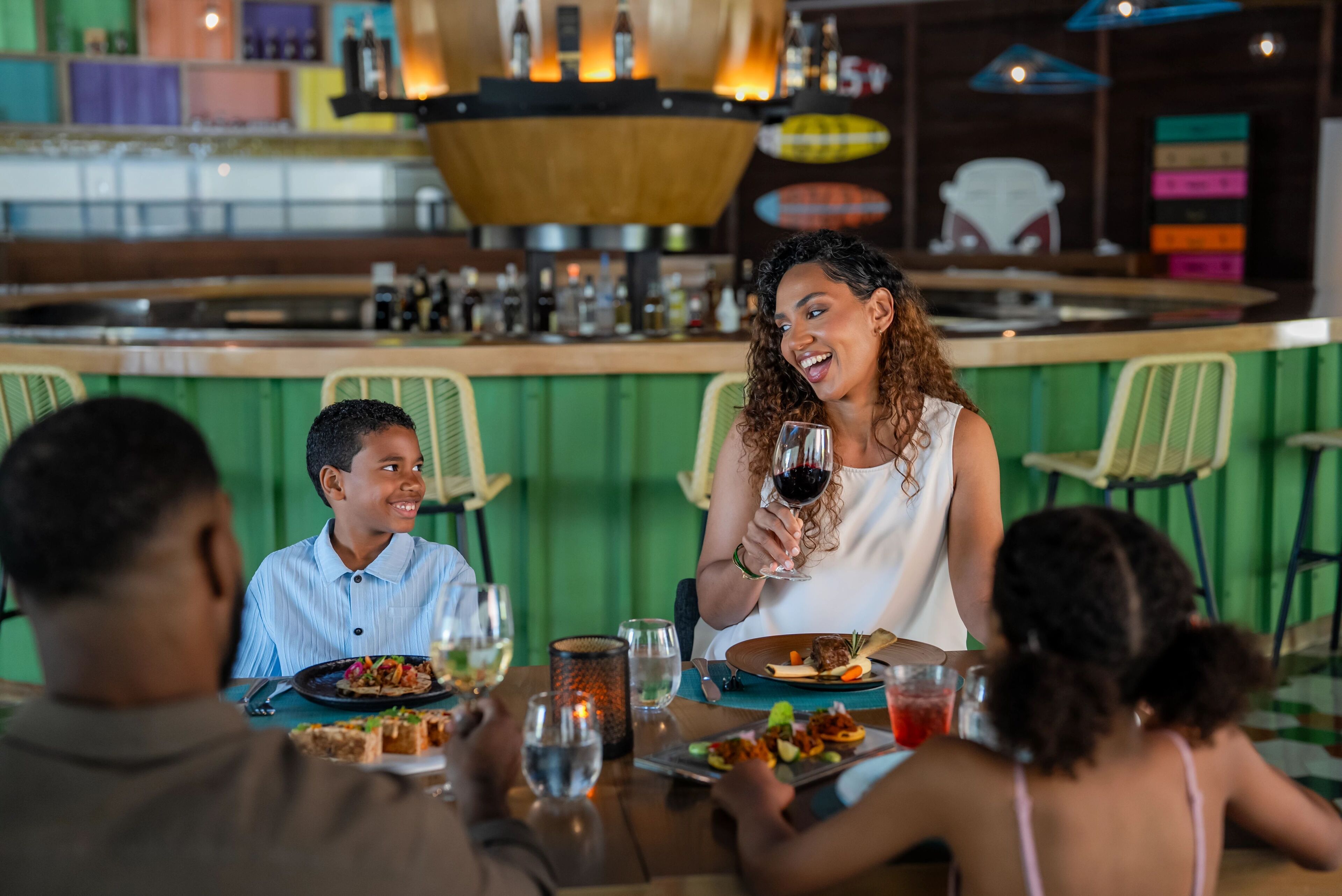 Ein Restaurant mit Barbereich, grünen Wänden und einer Theke mit verschiedenen Flaschen.