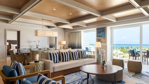 A spacious living area with a large sofa, a dining table, and a view of the ocean.