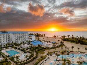 A resort with multiple swimming pools, a beach, and a view of the sunset over the ocean. - Dreams Cap Cana Resort & Spa - All Inclusive (Punta Cana)