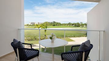 A balcony with two chairs, a small table, and a view of a golf course.