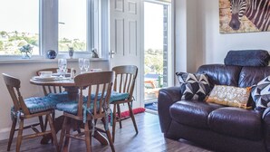 Uma área de refeições com mesa posta para dois, um sofá de couro e uma pintura de zebra na parede.