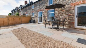 A stone building with a patio area, outdoor seating, and a wooden fence.