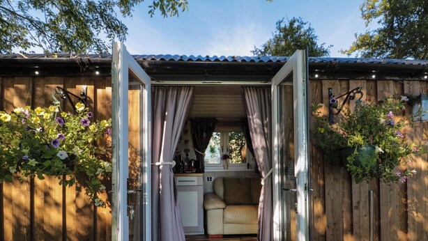 A cozy cabin with a sliding glass door leading to a small kitchenette and a seating area. - The Shepherd's Rest (Whitby)