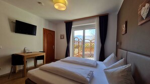 Ein Hotelzimmer mit Bett, Schreibtisch, Fernseher und Fenster mit Blick ins Freie.