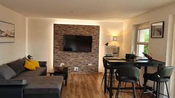 Apartamento Deluxe | Zona de estar | Televisión de pantalla plana de 32 pulgadas con canales por satélite