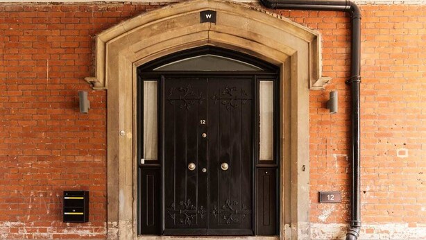 A black double door with a number "12" above it, set in a brick wall with a stone archway. - The Woolwich Retreat - Enticing 5bdr House With Parking (London)