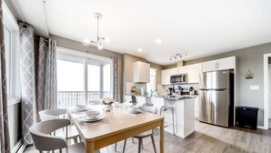 A modern kitchen with a central island, stainless steel appliances, and a dining area with a table and chairs.
