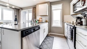 A modern kitchen with a central island, built-in dishwasher, and stainless steel appliances.