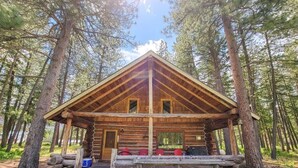 A log cabin with a wooden exterior, a porch, and a stone pathway leading to it. - Goat Wall Cabin: log cabin retreat on the meadow (Mazama)