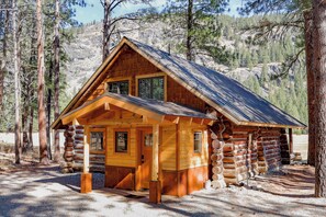 A log cabin with a gabled roof, wooden exterior, and a front porch.