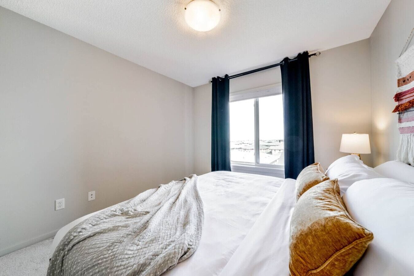 Une chambre d’hôtel avec un lit, une fenêtre avec des rideaux, une lampe et une vue sur la ville.
