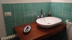 A bathroom with a sink, mirror, and green tiled walls.