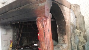A brick fireplace with a wooden arch and a stone wall.