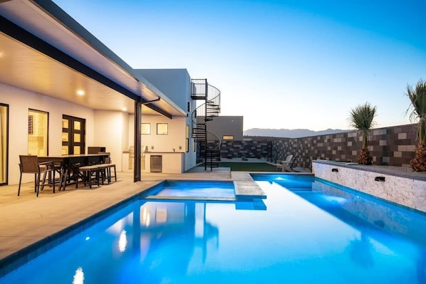 Un área de piscina moderna con comedor y una escalera de caracol.