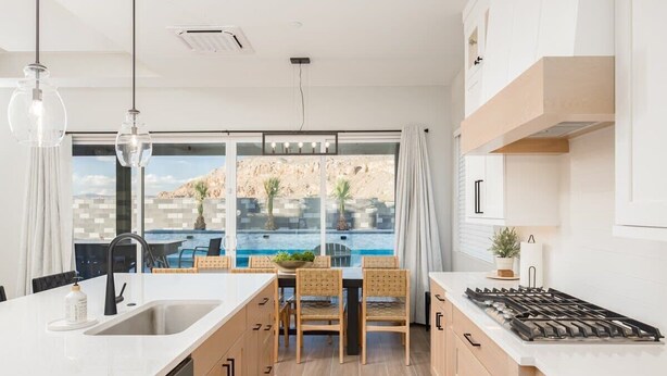 A modern kitchen with a large island, a gas stove, and a view of a pool and mountains. - The Gambit Luxury Zion Home Pool Hot Tub Sleeps 14 (Hurricane)
