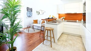 A modern kitchen with white cabinets, a wooden countertop, and a bar stool. - Young Spirit Apartment (Faro)
