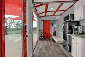 A modern kitchen with a red accent wall, a bench, and a view of the outdoors.