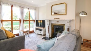 A living room with a fireplace, a television, and a large window with curtains. - Avenue Croft (Nottingham)
