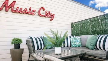An outdoor seating area with a sofa, chairs, and a table. A sign reading "Music City" is visible on the wall.
