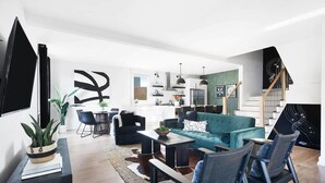Una sala de estar moderna con un sofá color turquesa, sillas negras y una zona de comedor con mesa y sillas.