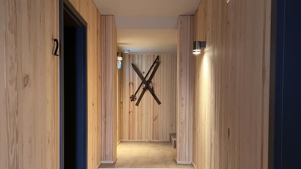 A hallway with wooden walls and a wooden floor, leading to a staircase. - Bergquell Willingen App. 2 (Willingen)