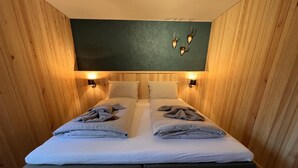 A double bed with two pillows and a blanket, wooden walls, and two wall-mounted lights. - Bergquell Willingen App. 2 (Willingen)