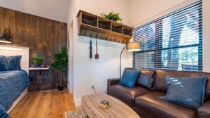 Uma sala de estar moderna com piso de madeira, um sofá de couro marrom, uma mesa de centro de madeira e uma estante embutida com plantas.