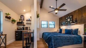 Quarto com cama, escrivaninha e ventoinha no teto.