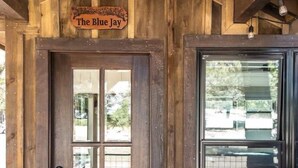 Uma porta de madeira com um painel de vidro e uma placa acima com a inscrição 'The Blue Jay'.