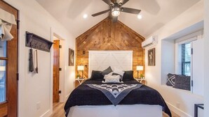 Quarto com uma cama grande, teto de madeira e ventilador de teto.