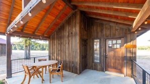Een houten chalet met een overdekte veranda, een eettafel en stoelen.