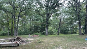 A wooded area with a pile of branches and a bench. - Primitive Campsites with water spigot, toilets, and wifi! (Bourbon)