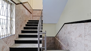 A staircase with marble steps and metal railings, leading to a landing with a black and white wall. - Itsy Hotels HSR Comfort (Bengaluru)