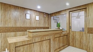 A reception area with a wooden reception desk, framed certificates on the wall, and a window with blinds. - Itsy Hotels HSR Comfort (Bengaluru)