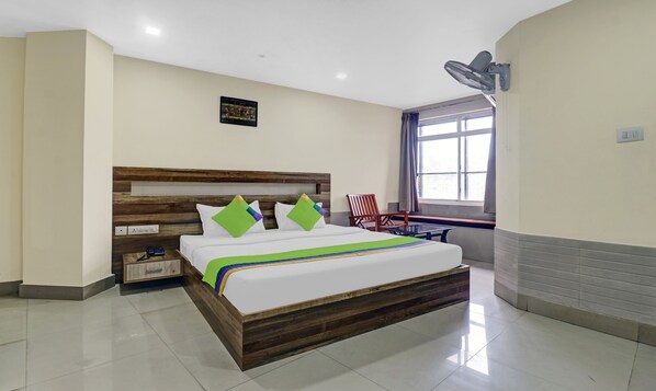 Quarto de hotel com cama de madeira, uma escrivaninha e uma cadeira.